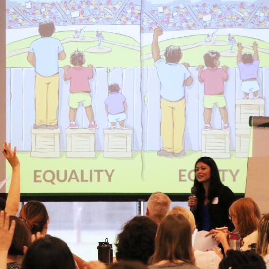 Presenter in front of audience with equality vs. equity drawing