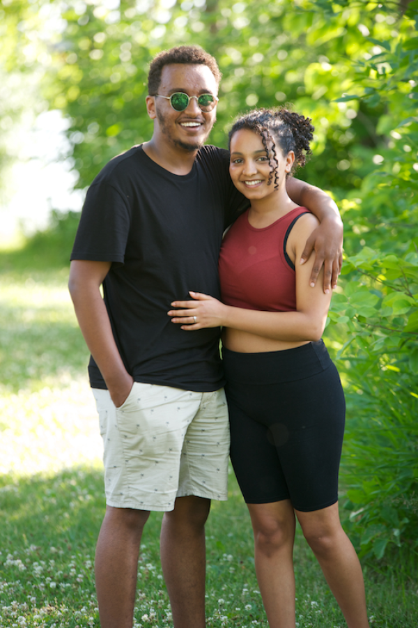 A young couple posing together outside on a bright day.