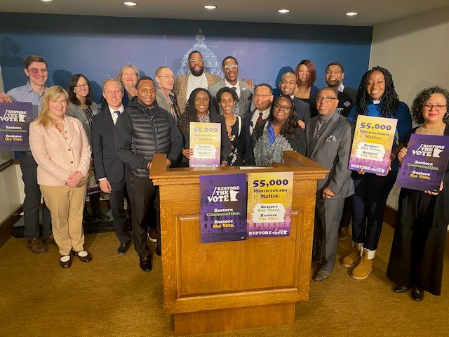 Group of people standing behind a podium with advocacy signs