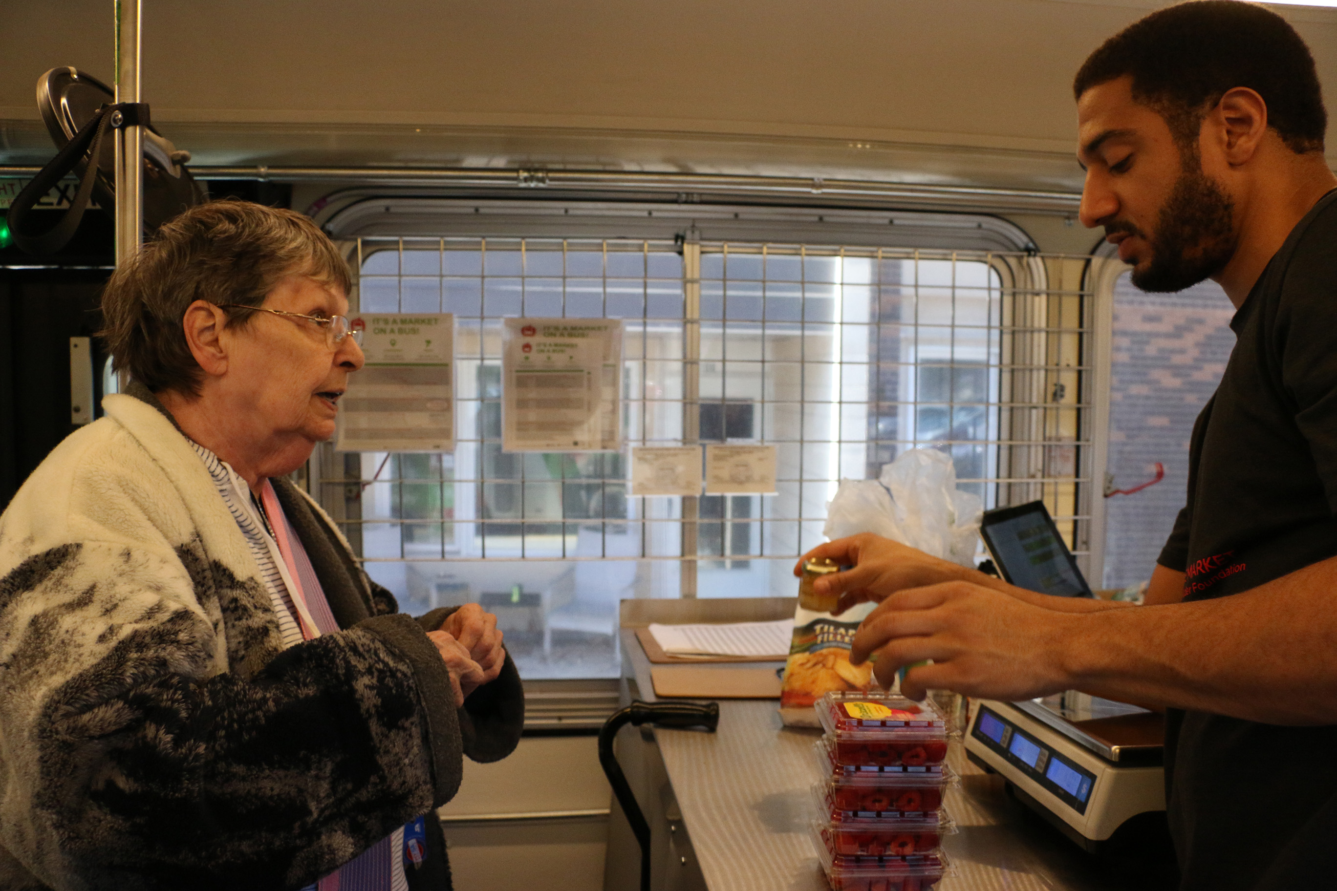 older woman shopping in market, mobile market staff helps older woman, market diversity