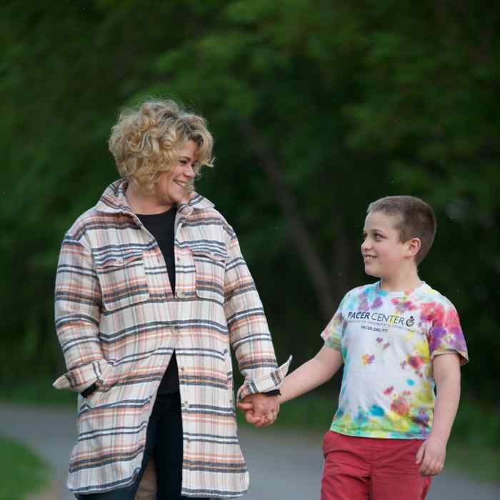 white-appearing woman holding hands and looking at white-appearing boy