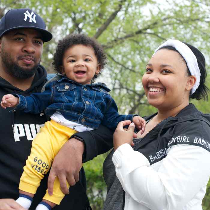 Black family of mother, father and child smiling and enjoying the park.