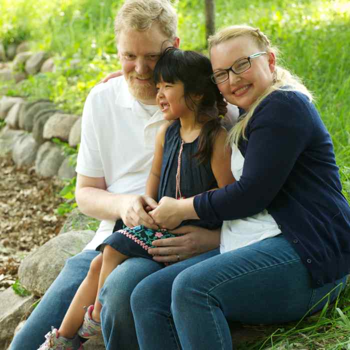 Father, mother and daughter sitting outside