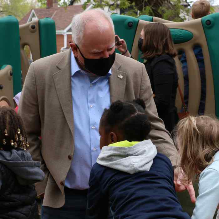 Governor Tim Walz wearing a mask and speaking with three young children on a playground