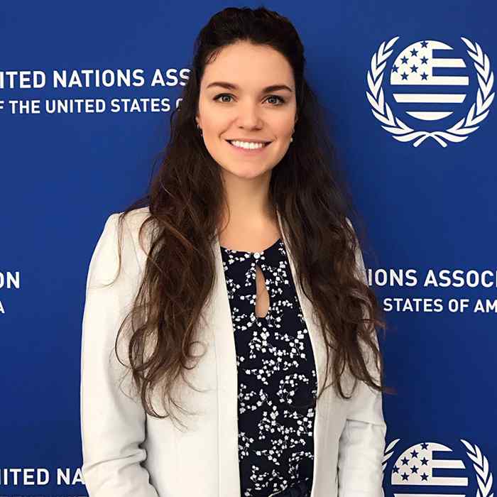 A woman stands in front of a United Nations Association of the United States backdrop. 