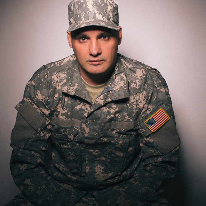 A seated servicemember in army fatigues.