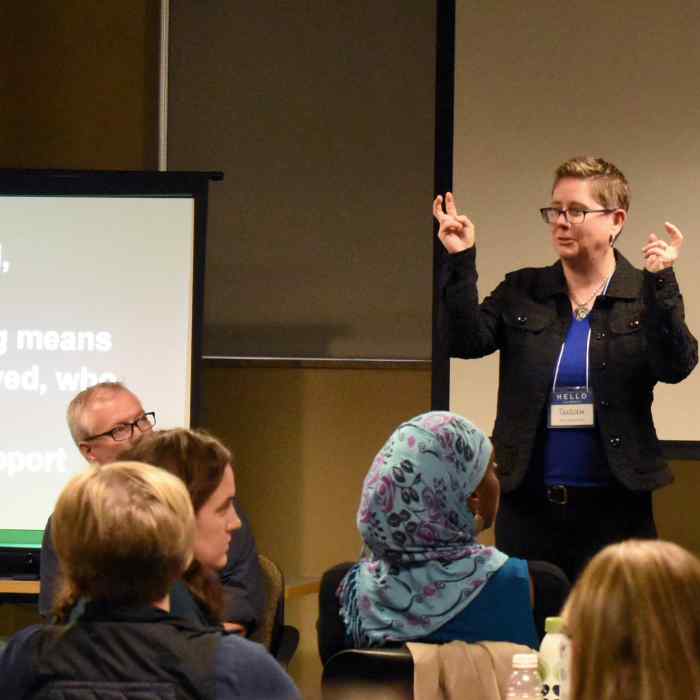 A woman presents before a room full of seated people.