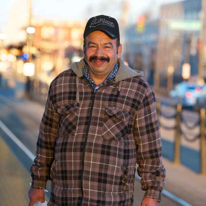 Man with mustache holding bags standing outside