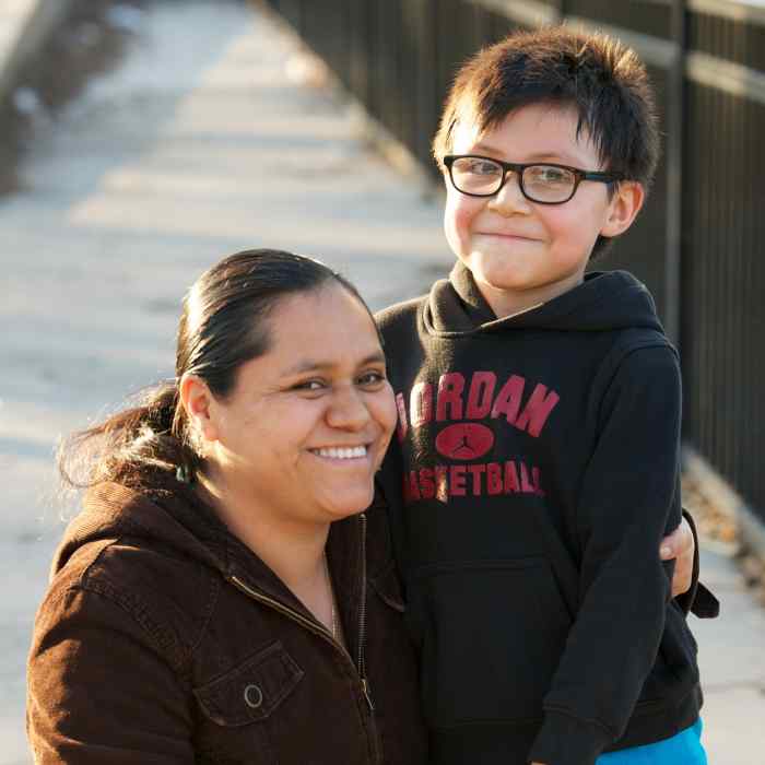 Mother kneeling next to young son with her arm around his shoulder