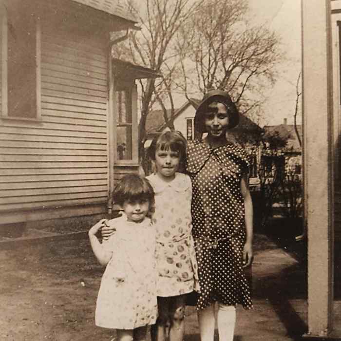 Three girls in dresses posing together in the 1920s