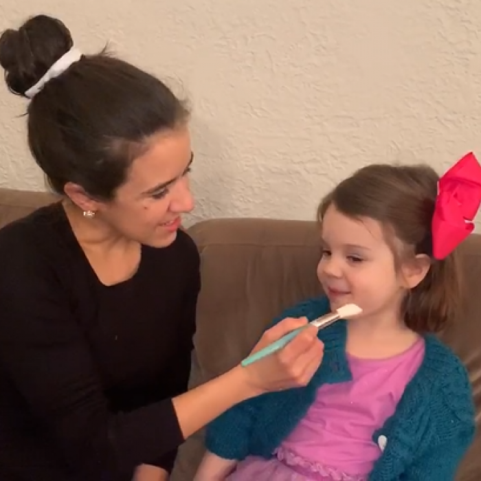 Mother painting imaginary picture on daughter's face during play therapy