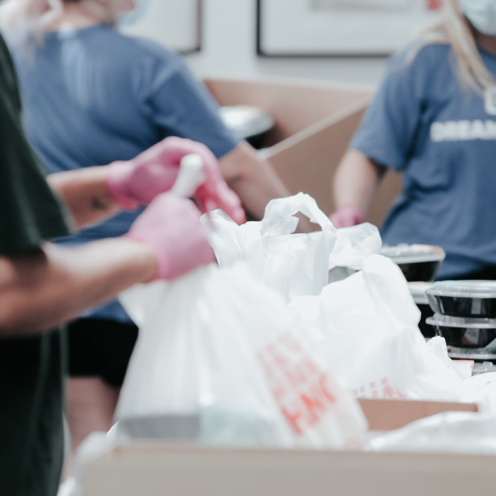 Three people holding plastic bags at a food distribution site