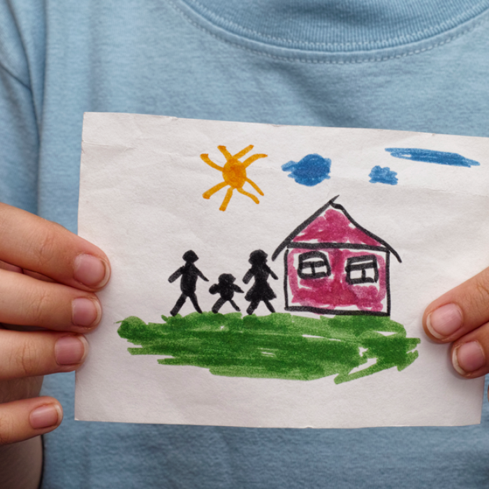 Child holding painting of home in front of them