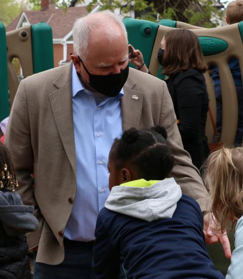Governor Tim Walz wearing a mask and speaking with three young children on a playground