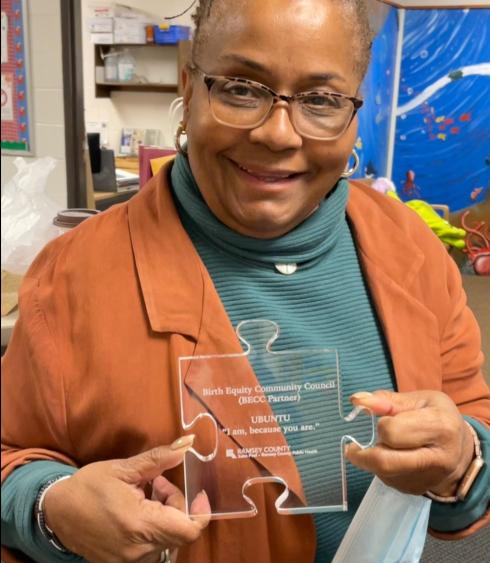 Sameerah Bilal-Roby holding glass, puzzle-shaped community partner award from the Birth Equity Community Council