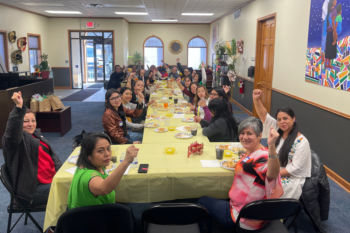 A group of women gathered along a long table enjoying a meal together.