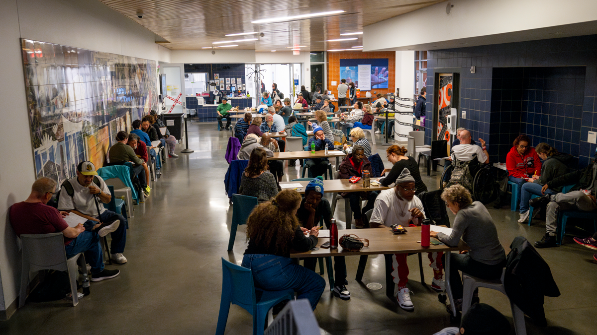 A cafeteria space is filled with people conducting one-on-one interviews.