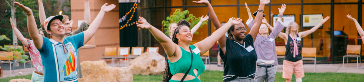 A line of eight people smiling with hands overhead at Wilder Center