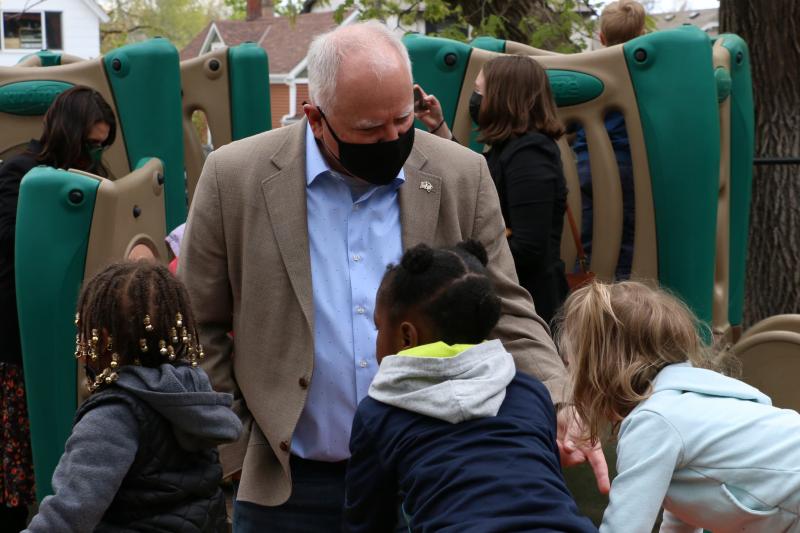 Governor Tim Walz wearing a mask and speaking with three young children on a playground