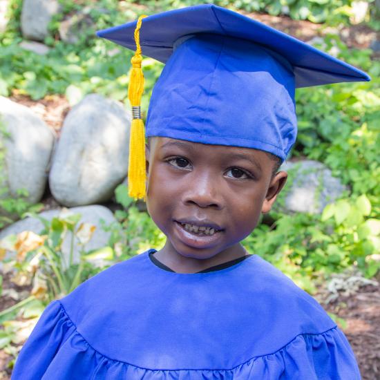 Preschool-age boy wearing blue graduation cap and gown