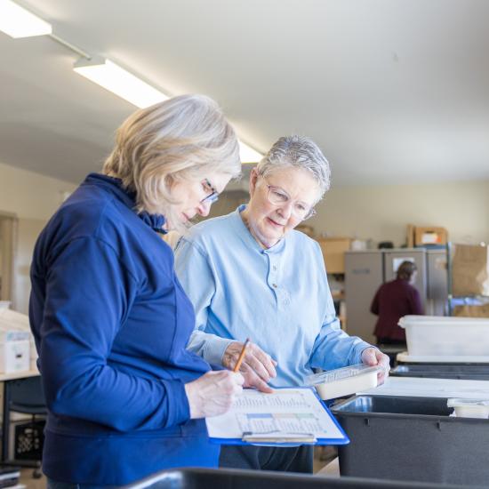 Two Meals on Wheels volunteers review the meal list for clients.