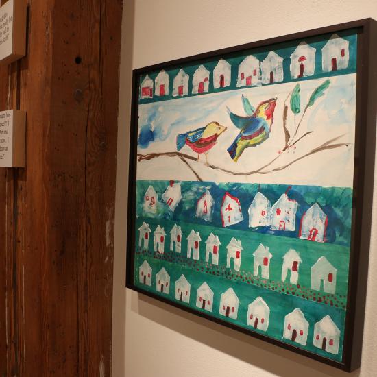 Bird and house painting hanging in gallery