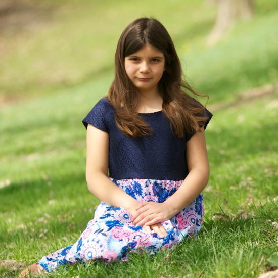 Girl with shirt and skirt sitting in green grass