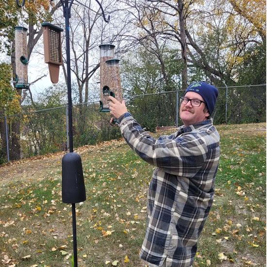 Dan Swanson, Wilder research staff member, adding birdseed to a bird feeder
