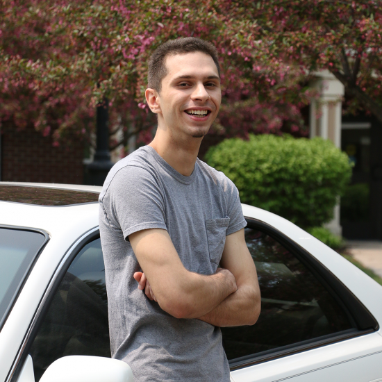 Sebastian Dina, participant in Wilder supportive housing services, poses in front of his car outside Lincoln Place supportive housing development in Eagan, Minnesota
