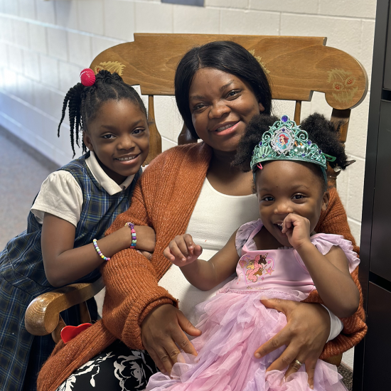 Theodora sits in a rocking chair with two daughters