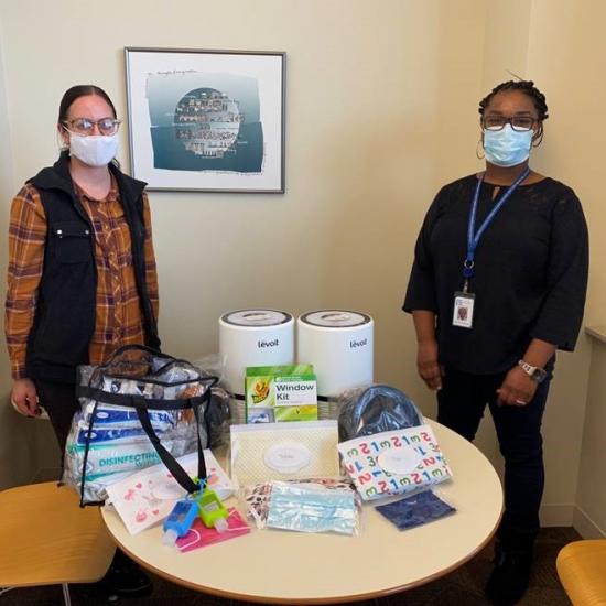 Two Wilder employees stand behind protective equipment for participants in Homework Starts with Home, a stable housing initiative