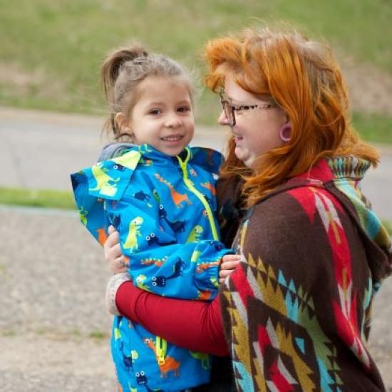 Young woman with red hair holding little girl in her arms