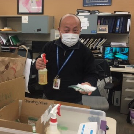 Man with mask holding up bottle of disinfectant at Wilder Center 