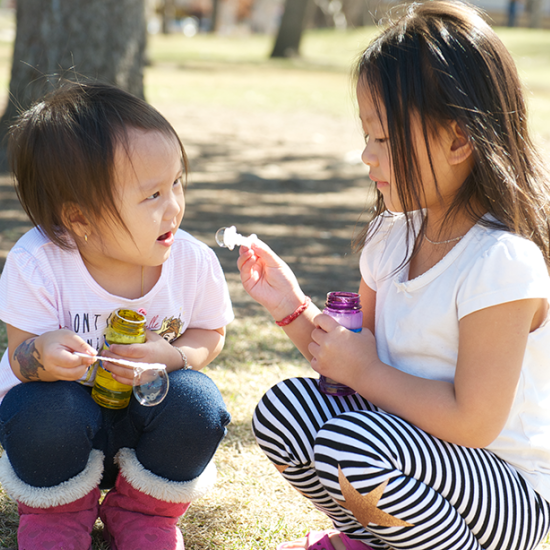 Two children playing with bubbles on a playground in Saint Paul, MN