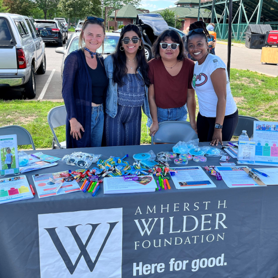 A picture of four people standing together behind a table with Wilder information at an outdoor event