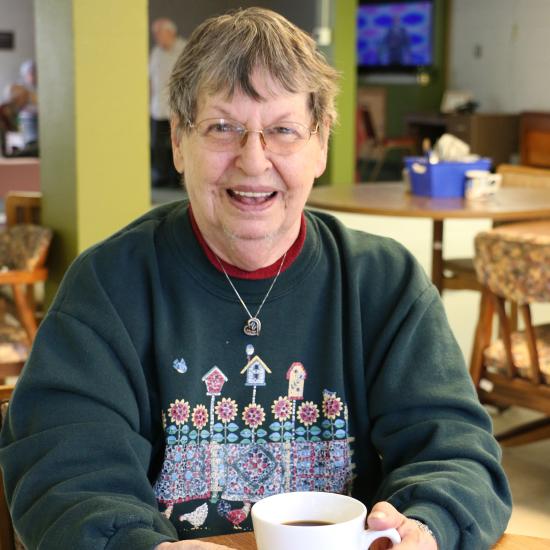 older woman smiling with coffee, mobile market customer