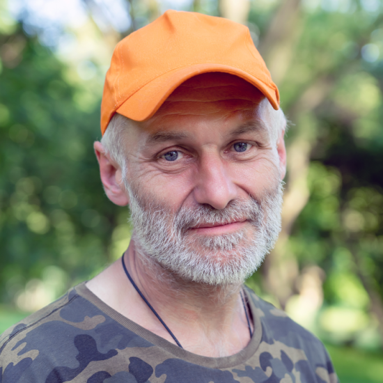 A bearded man in a cap and camouflage t-shirt.