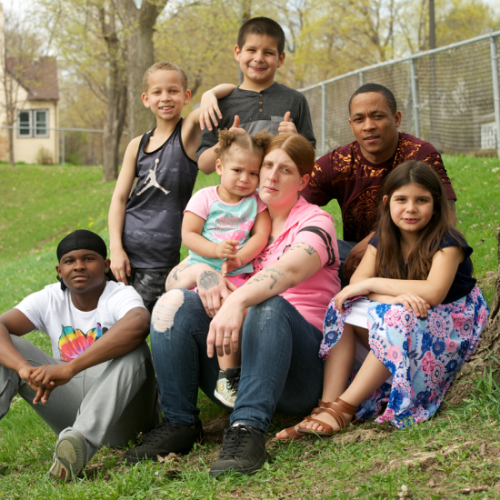 Family with children smiling with house in the background