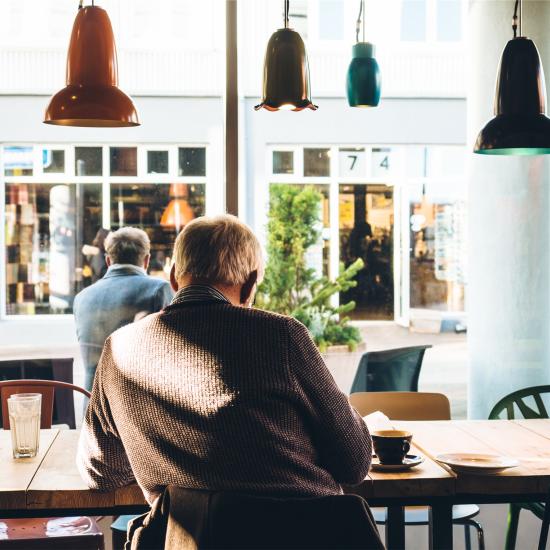 Older man sitting at table facing away from camera