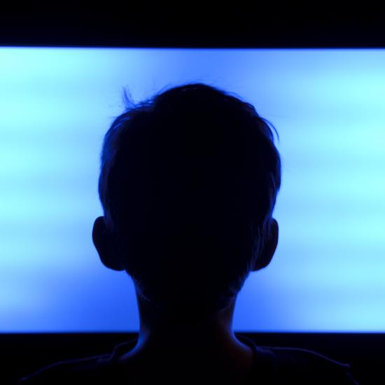 Child silhouette in front of blank TV screen