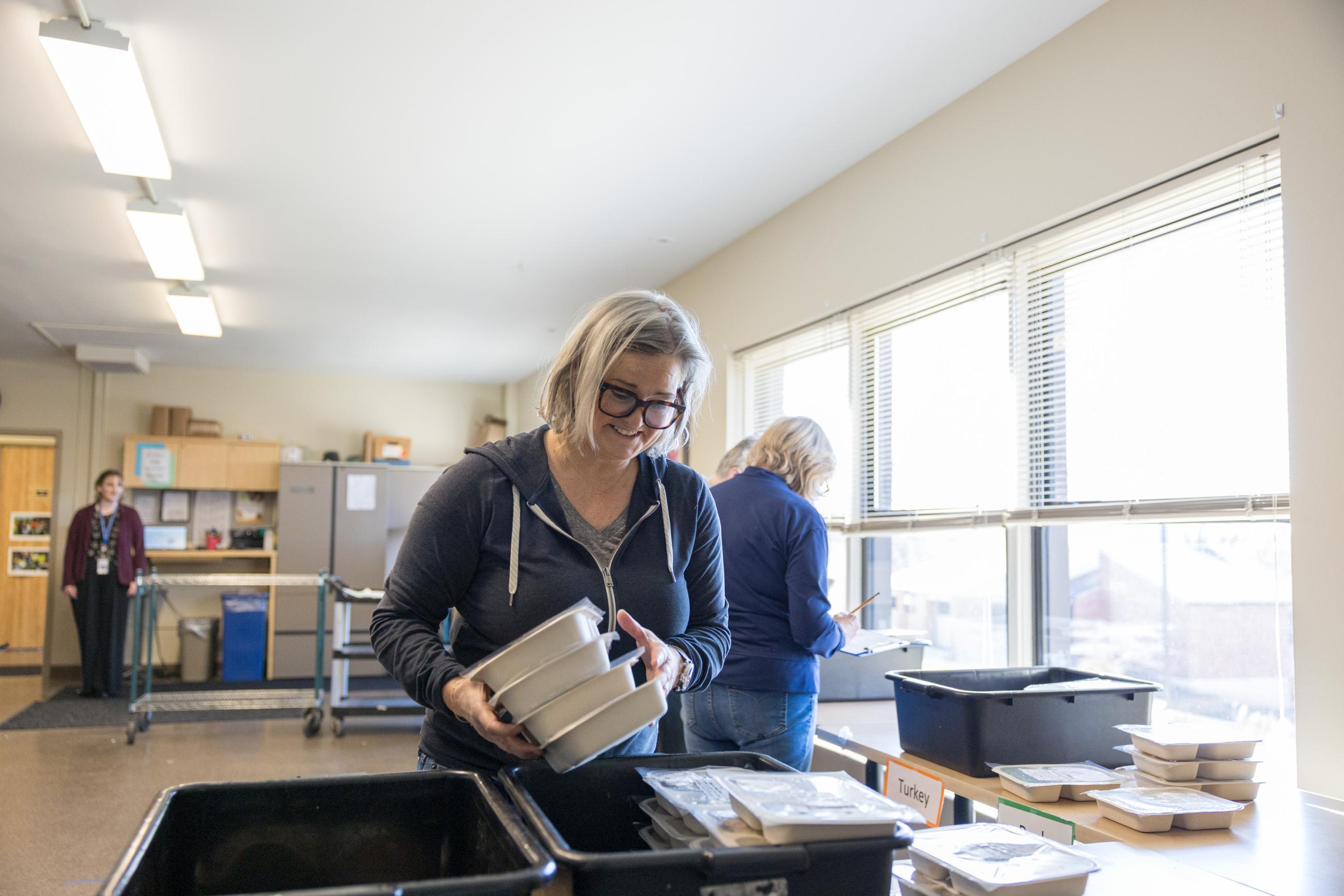 Meals on Wheels volunteer looking through meals.