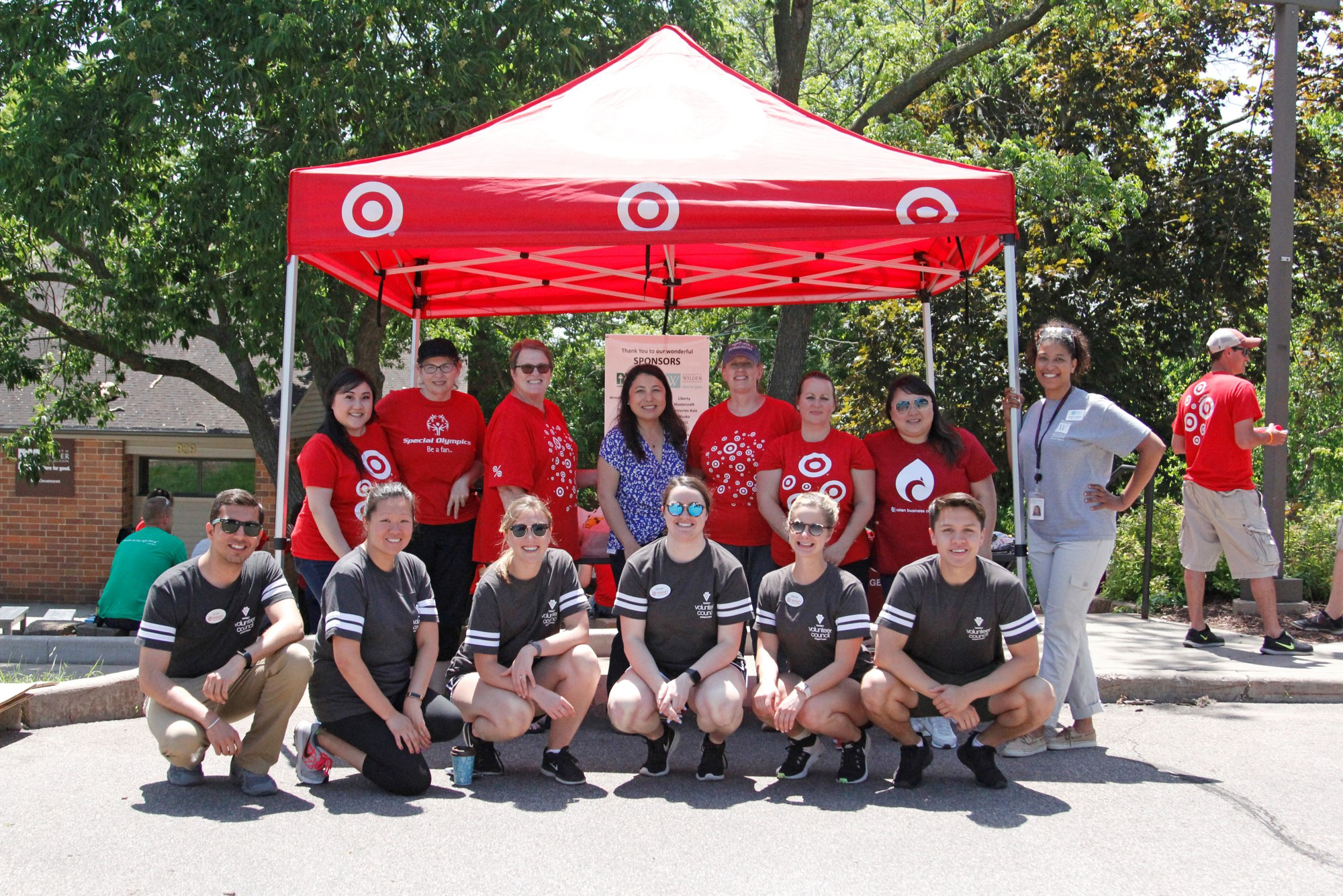 Two rows of volunteers posing under a tent during a construction project at the Wilder Center for Social Healing.