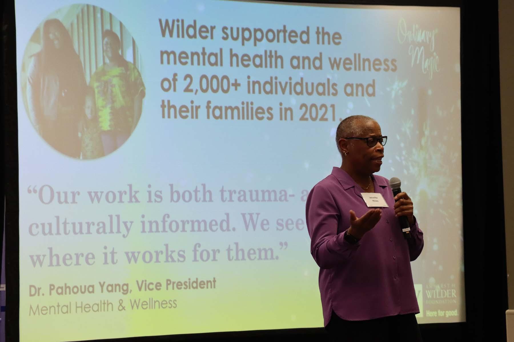 Dr. Jennifer Hines stands in front of a screen with facts about Wilder mental health services during Ordinary Magic 2022