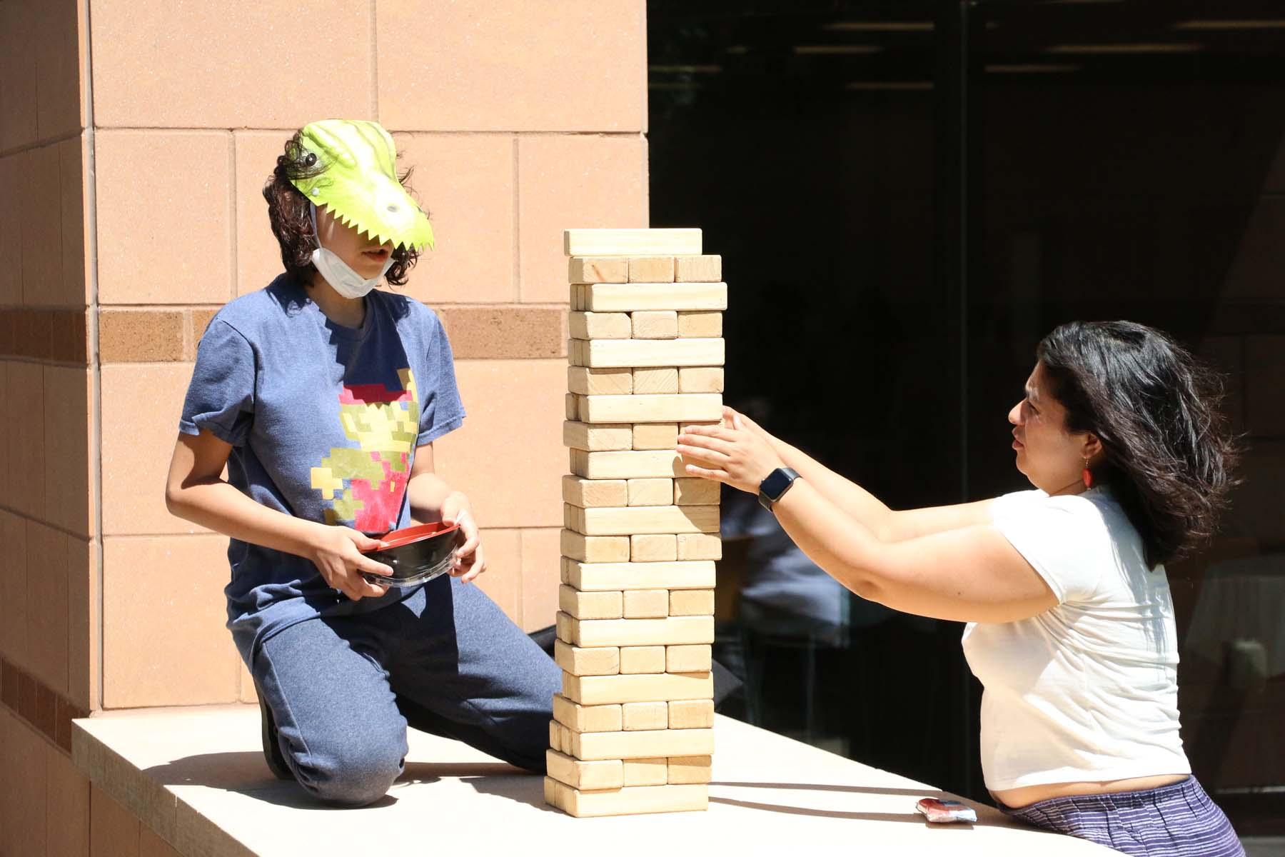 Two people playing with large jenga blocks at an outdoor party