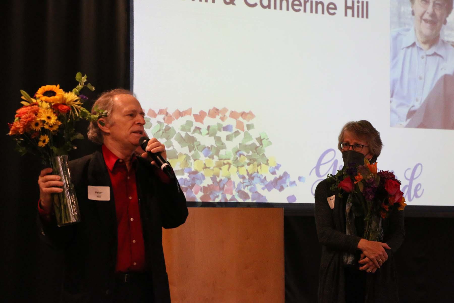 Man holding flowers speaks into a microphone at the 2022 gratitude gathering for Wilder supporters