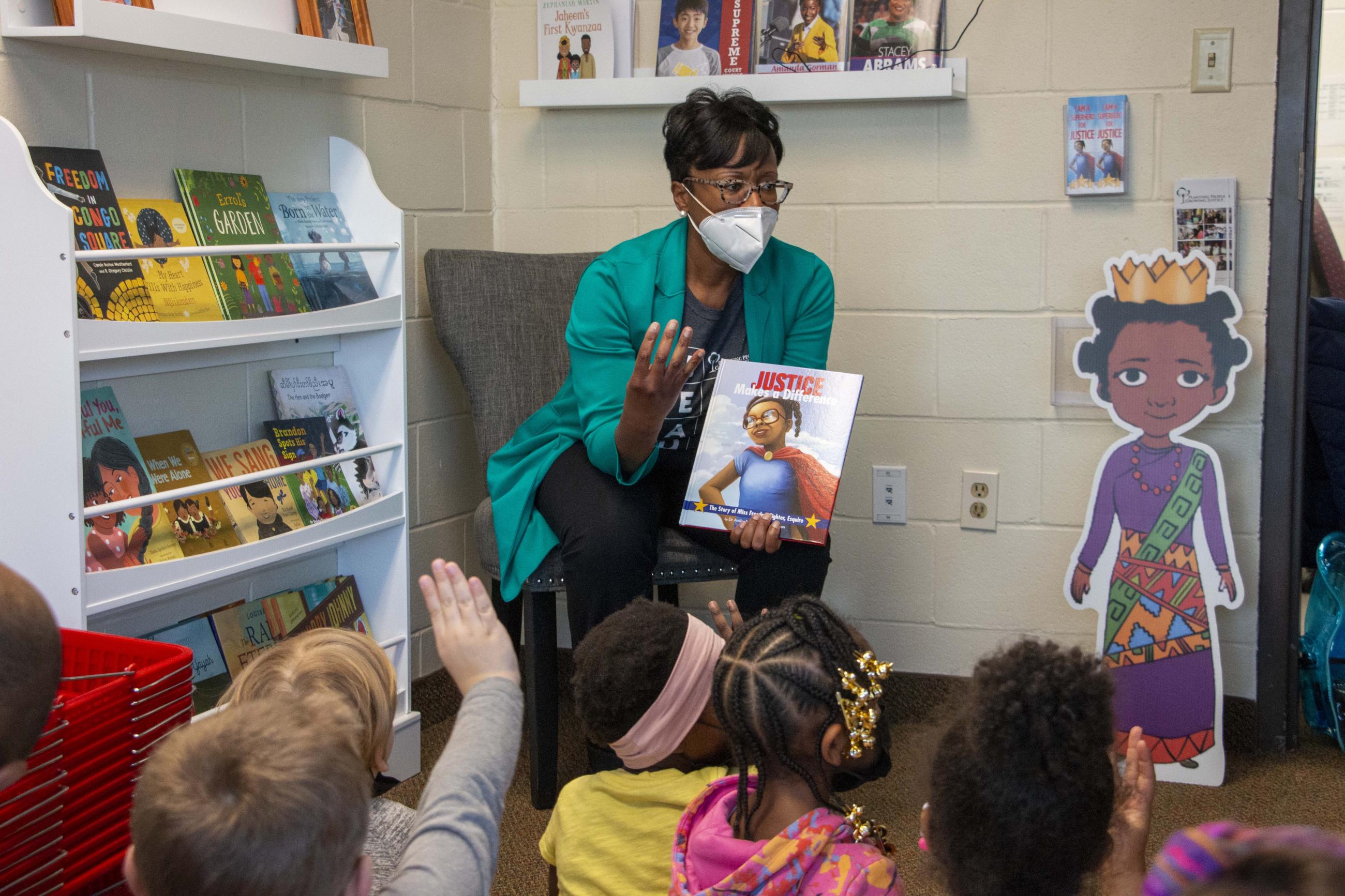 Woman sitting on a chair reading to children 