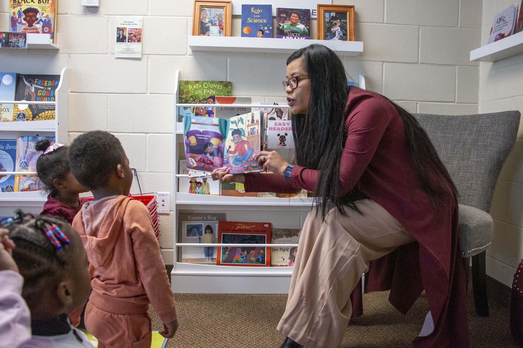 Small children watch as author Thuba Nguyen reads her book in the R.A.W. Library at the Wilder Child Development Center