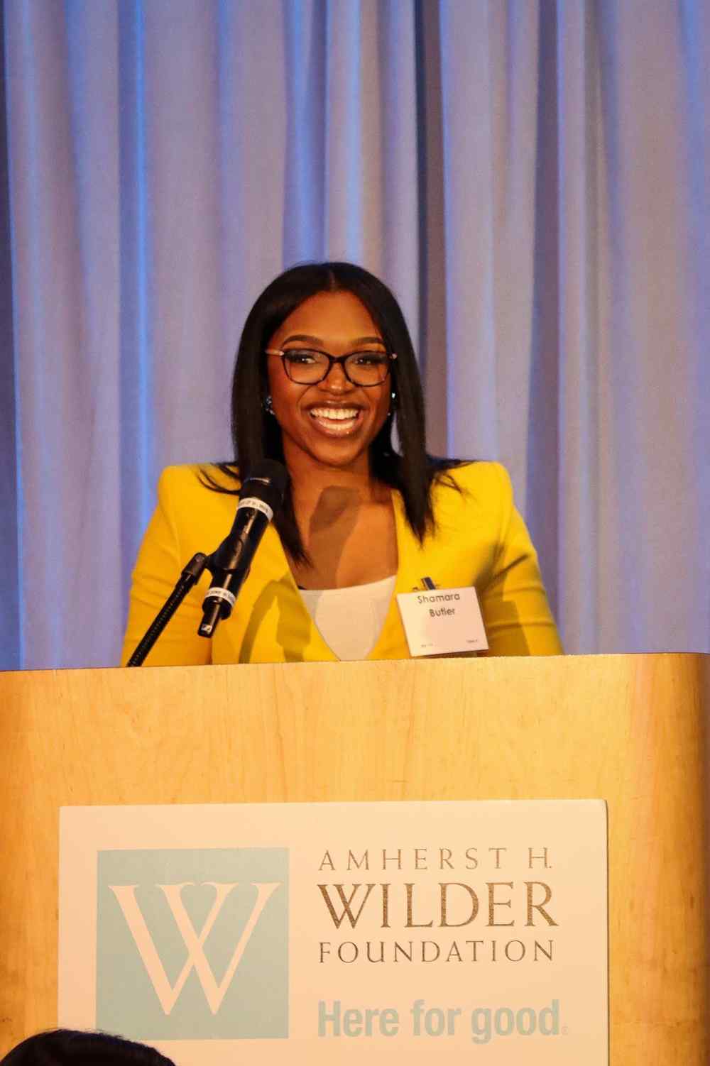 A woman (Shamara Butler) behind a podium speaking at an event at Wilder Center.
