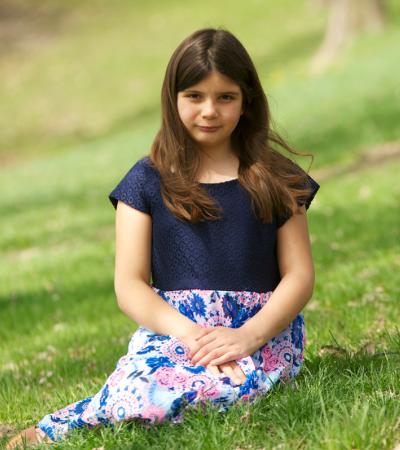 Girl with shirt and skirt sitting in green grass
