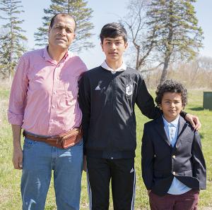 A picture of an man standing next to his two sons outdoors